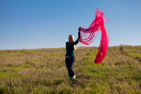 young beautiful woman jumping with tissue into the field against the skyの写真素材