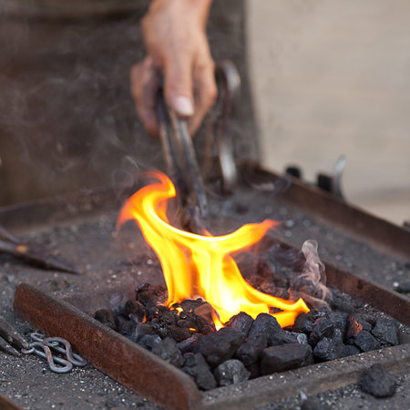 embers, fire, smoke, tools and the hands of a blacksmithの写真素材