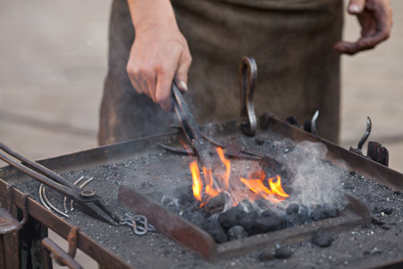 embers, fire, smoke, tools and the hands of a blacksmithの写真素材