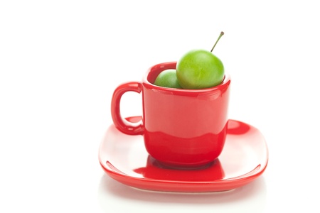 green plum  in the red cup isolated on whiteの写真素材