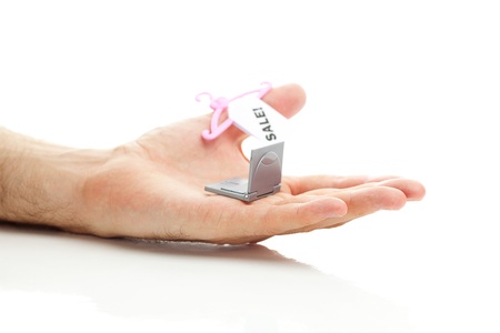 miniature laptop and hanger with a price tag sale in hand isolated on whiteの写真素材