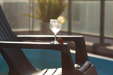 Swimming pool, lounge, a wine glass with ice, lemon and strawberry