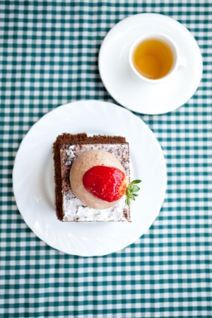 beautiful cake with strawberry and tea on plaid fabricの写真素材