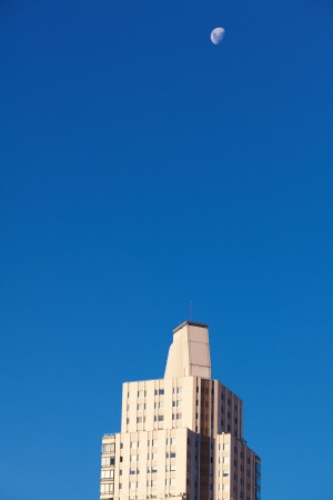 Beautiful modern office buildings and the moon against the blue skyの写真素材