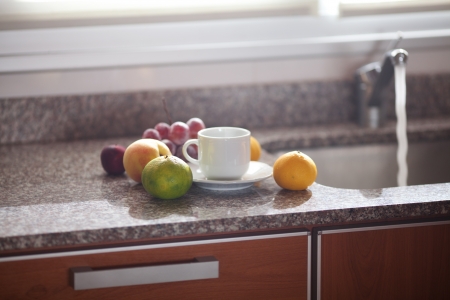 cup, fruits and faucet on the kitchenの写真素材
