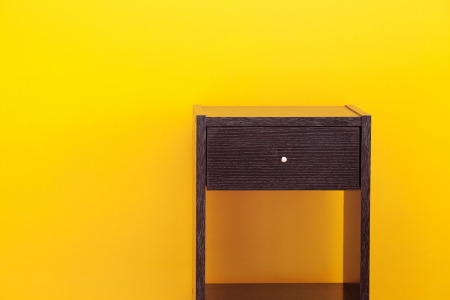 bedside table against a yellow wall in the apartmentの写真素材