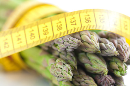 asparagus tied with measuring tape isolated on white
