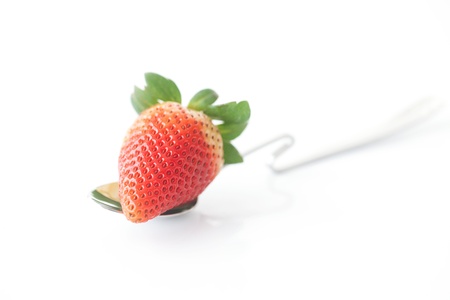 big red strawberry and spoon isolated on whiteの写真素材
