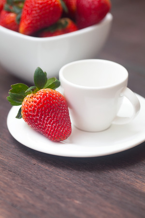 red juicy strawberry in a bowl and cup on a wooden surfaceの写真素材