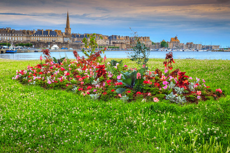 Spectacular walled city and luxury yacht harbor with blossoming colorful flowerbeds in summer city park, Saint Malo, Brittany region, France, Europeの写真素材