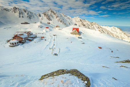 Spectacular winter landscape in Fagaras mountains with famous frozen Balea lake and wooden houses,...