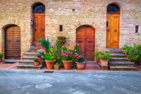 Traditional Tuscany architectural view. Fantastic entrance and paved street decorated with colorful flowers in Pienza, Tuscany, Italy, Europeの写真素材