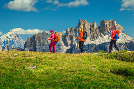 Sporty healthy active woman group of hikers with colorful backpacks and mountain equipment walking on the mountain ridge, Dolomites, Italy, Europeの写真素材