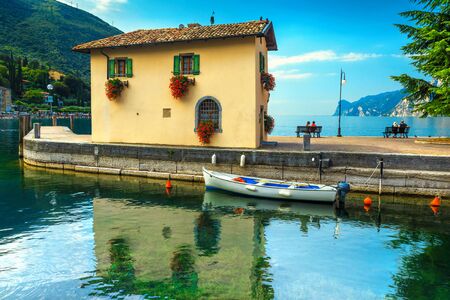 Beautiful summer morning landscape, fishing boat in harbor and high mountains in background, Torbole touristic town, Italy, Europeのeditorial素材