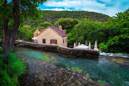 Popular mediterranean touristic and hiking location with Krka waterfalls. Brook with cascades and stone house near Sibenik touristic resort, Dalmatia, Croatia, Europeの写真素材