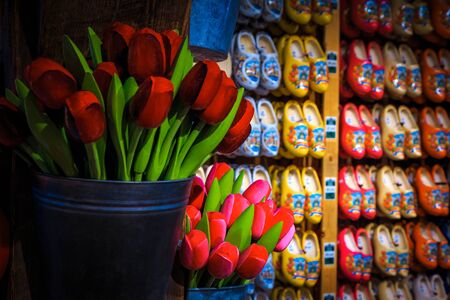 Stunning colorful bouquets of wooden tulips in the bucket and wooden shoes in row on the wall. Dutch souvenir shop decoration with handmade gift objects, Amsterdam, Netherlands, Europeの写真素材