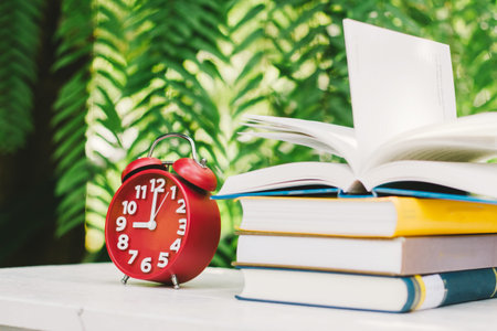 Education concept, Book and Clock with green blur background.,Books stacking.