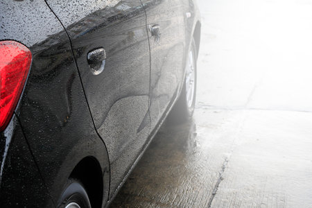 Raindrops on a car surface,Car wash, black car in automatic car washの写真素材