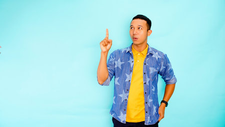 happy handsome Asian man pointing hand aside to copy space while standingの写真素材