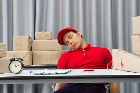 SME man Delivery  tired overworked sleeping on packaging boxesの写真素材
