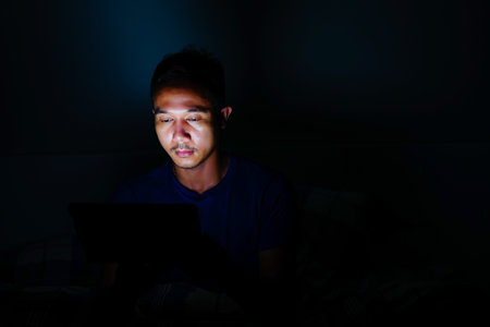 man using tablet to reading in bed and turning off the lights before getting some shut-eye sleep....