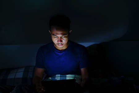 man using tablet to reading in bed and turning off the lights before getting some shut-eye sleep. working on bedの写真素材