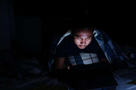 man using tablet to reading in bed and turning off the lights before getting some shut-eye sleep. working on bedの写真素材