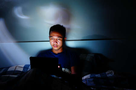 man using tablet to reading in bed and turning off the lights before getting some shut-eye sleep. working on bedの写真素材