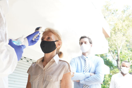 Disease control experts  use an Infrared thermometer equipment to check the temperature on the...