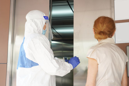 Disease control experts  use an Infrared thermometer equipment to check the temperature on the forehead and use alcohol gel to screen the patients addicted to Covid before entering the building.の写真素材