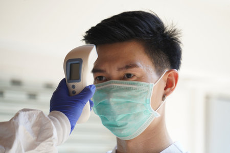 Disease control experts  use an Infrared thermometer equipment to check the temperature on the...