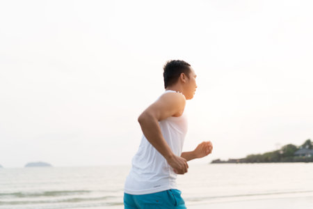 asian sport man running along seaside. running on beach with healthy toned legs body, Hamstring...