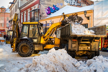 Uzhgorod, Ukraine - January 19, 2017: The tractor loads cleaned snow on the truck in the city...