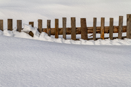 Wooden fence in the snow at the edge of a mountain village in the Carpathian Mountains.の写真素材