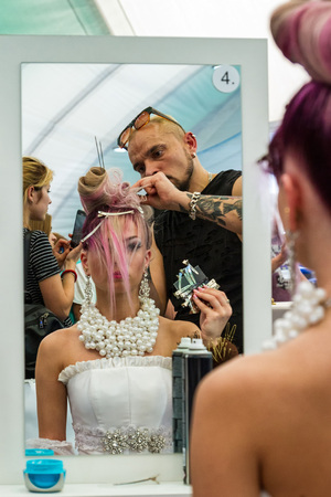 Uzhhorod, Ukraine - May 19, 2017: Hairdresser makes wedding hairstyle during the International Beauty Industry Competition Royal Buauty Carpathian Cup 2017. Displays in the mirror.のeditorial素材