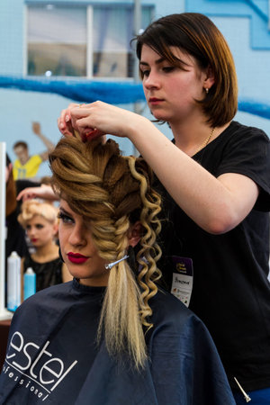 Uzhhorod, Ukraine - May 19, 2017: Hairdresser makes wedding hairstyle during the International Beauty Industry Competition Royal Buauty Carpathian Cup 2017.のeditorial素材