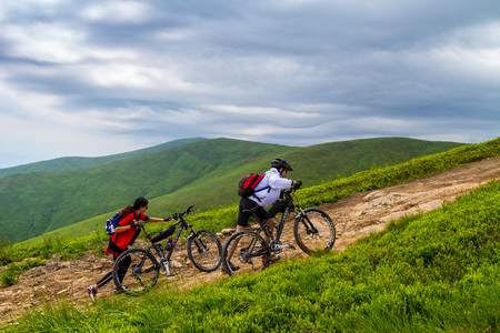 Pylypets, Ukraine - June 25, 2017: Cyclists pushing bicycles during a climb to the peak of Mount Hymba in the Carpathians near the village of Pylypets.のeditorial素材