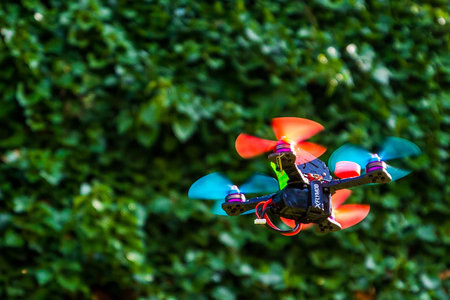The cropped shot view of a small sport drone flying against a wall with green ivy.のeditorial素材
