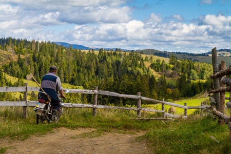 Pylypets, Ukraine - September 15, 2017: A local farmer riding a motorbike on a mountain road in the Carpathians on a beautiful sunny morning in early autumn.のeditorial素材