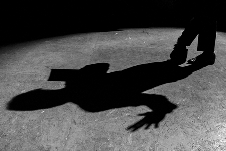 The shadow of a man reading a newspaper in the dark under a lantern. Black and white photo.の写真素材