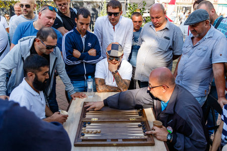 Men playing backgammon game in the park. Ukraine, Uzhgorod, September 15, 2019.