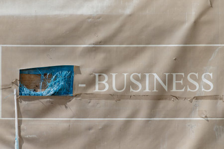 Uzhgorod, Ukraine - April 9, 2020: Hole in the banner with the inscription Business on the fence of...