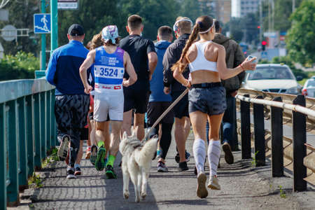 Uzhgorod, Ukraine - June 7, 2020: A group of young people run across the bridge while relaxing quarantine in Ukraine. Participants in a running event ran a distance of 10 km.のeditorial素材