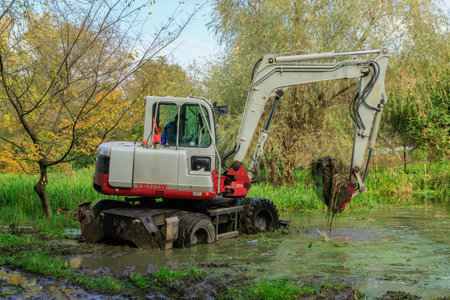 Beregovo, Ukraine - October 20, 2020: Excavator clean the riverbed from silt and debris after the...