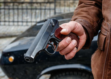 Russian semi-automatic Makarov pistol in a man's hand on the background of a black retro car.の写真素材