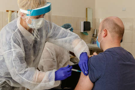 Uzhgorod, Ukraine - March 26, 2021: A doctor immunizes veterans of the Ukrainian army against Covid-19 with Ð¡ovishield vaccine at the vaccination point.のeditorial素材