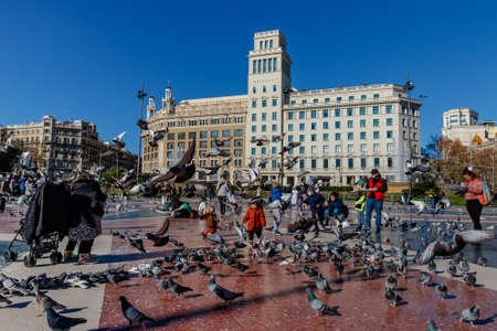 Barcelona (Catalonia, Spain) - January 6, 2022: Tourists feed pigeons in Plaza Catalunya in Barcelona.のeditorial素材