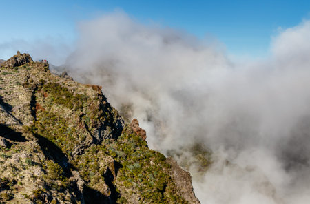 Clouds envelop the awe-inspiring majestic mountains with their rugged terrain and dark shadows. View from the top of Pico do Arieiro on the island of Madeira (Portugal).の写真素材