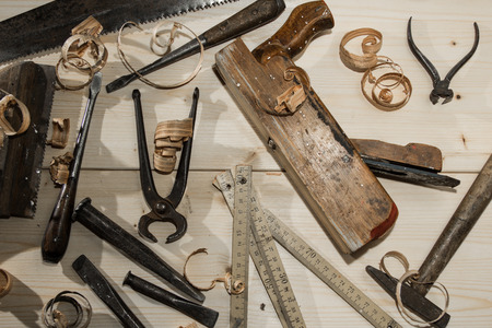 old woodworks tools: wooden planer, hammer, chisel in a carpentry workshop on wood backgroundの写真素材