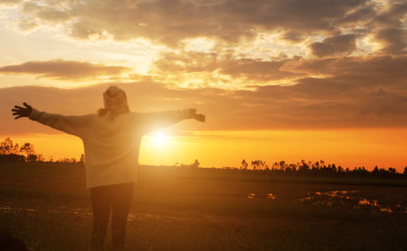 Silhouette of woman praying over beautiful sky backgroundの写真素材